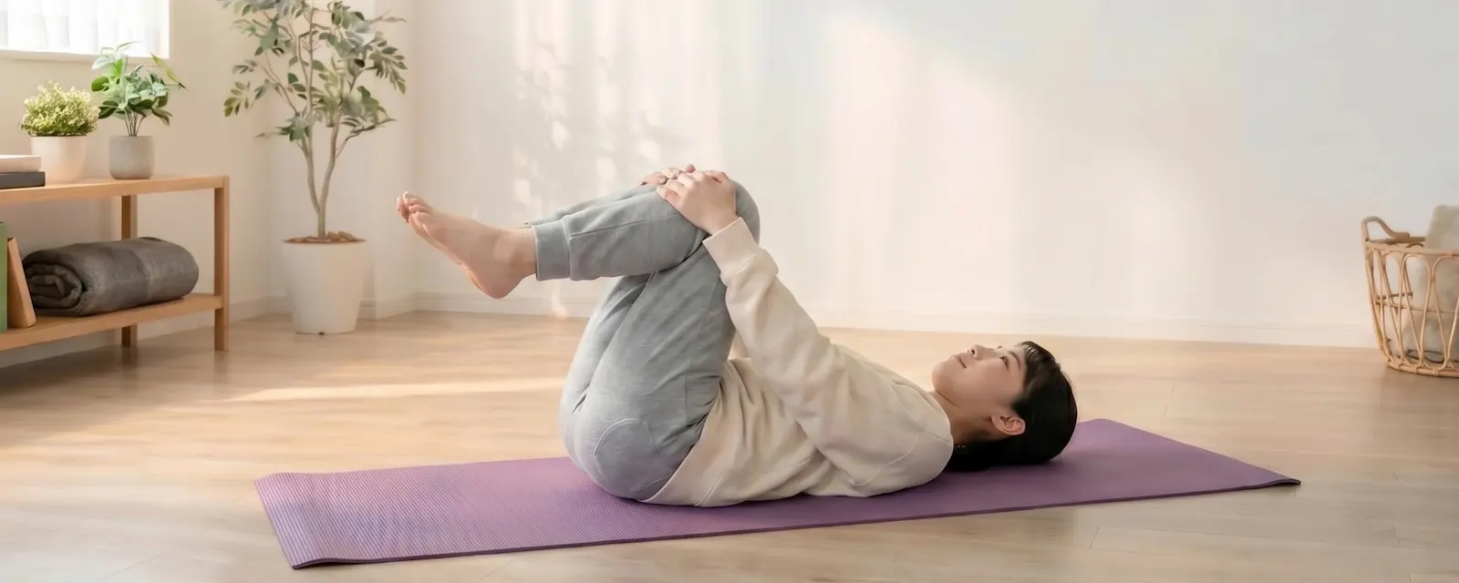 仰向けで腰まわりをほぐすストレッチをする女性